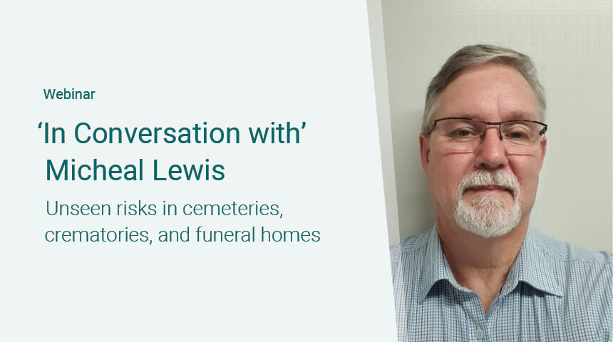 Webinar titled 'In Conversation with Michael Lewis: Unseen risks in cemeteries, crematories, and funeral homes.' The image shows Michael Lewis, a man with glasses, gray hair, and a beard, wearing a light blue checkered shirt, standing against a plain background.