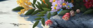 Close-up photograph of a bouquet of flowers resting on a marble surface, featuring a variety of colorful blossoms, including pink and yellow flowers, with green leaves gently arranged around them.