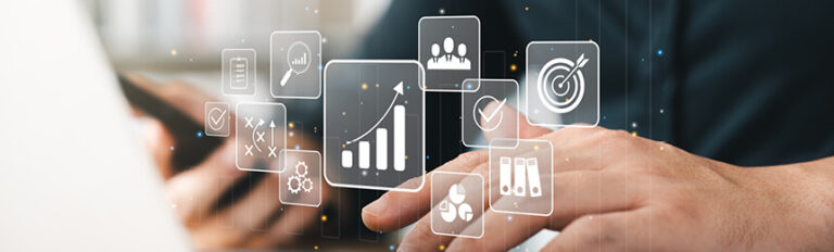 Close-up photograph of hands interacting with a laptop, with floating digital icons representing business metrics, analytics, and goals, such as a graph, target, and checklist, overlaying the image.